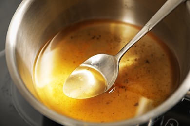 Photo of Used cooking oil and spoon in saute pan on stove, closeup