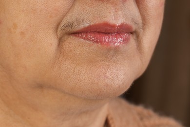 Senior woman with mustache on blurred background, closeup