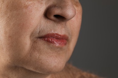 Senior woman with mustache on grey background, closeup. Space for text