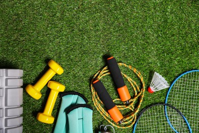 Photo of Different gym stuff on artificial green grass, flat lay. Space for text