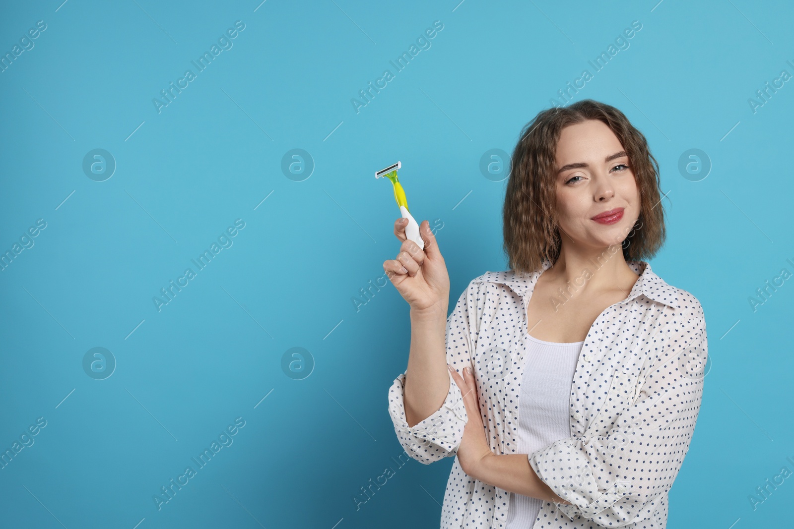 Photo of Beautiful woman with razor on light blue background, space for text. Hair removal tool