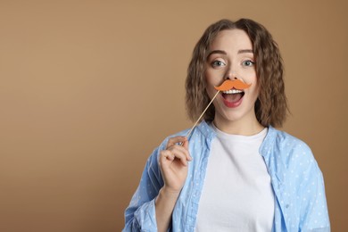 Woman with fake paper mustache on beige background. Space for text