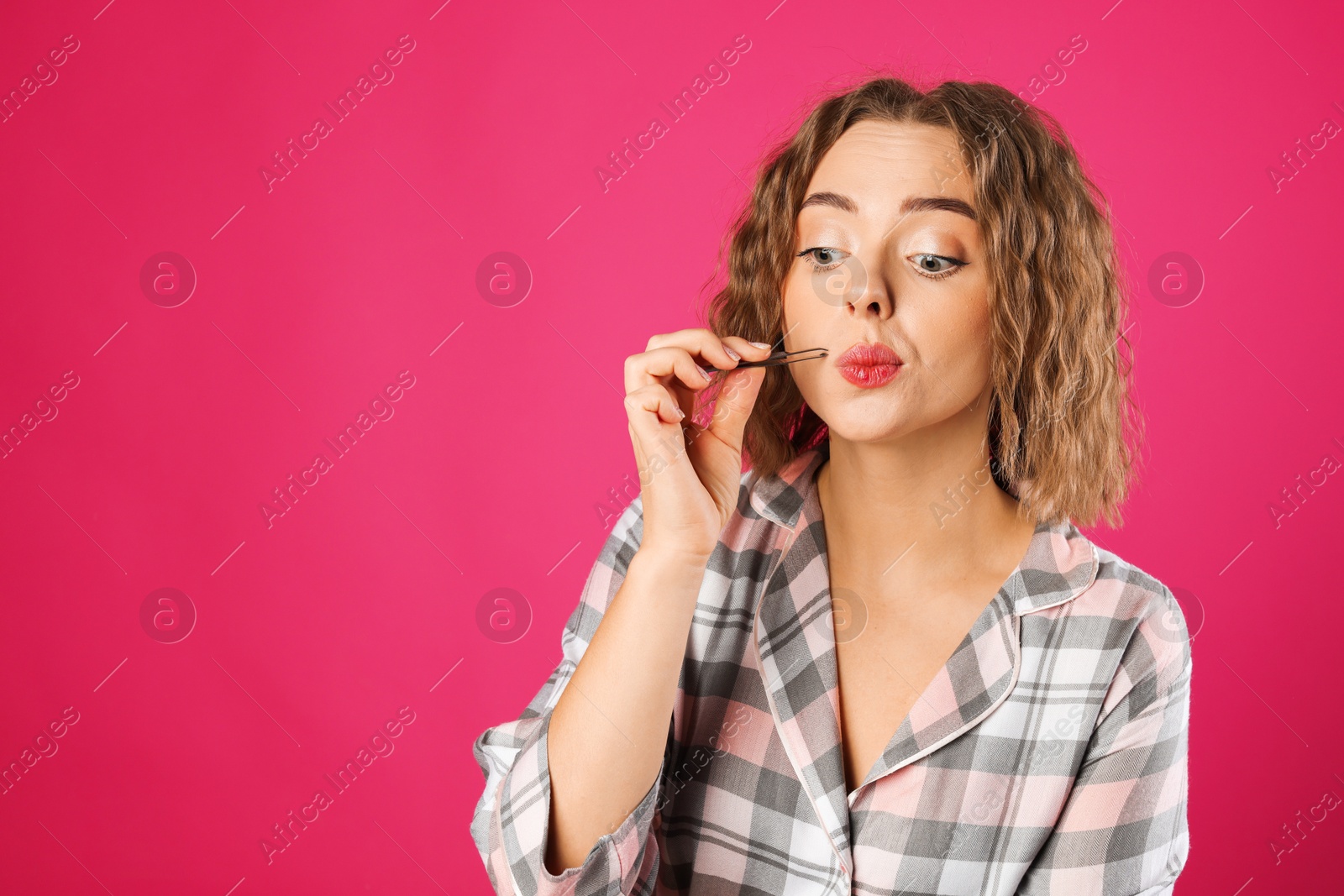 Photo of Beautiful woman plucking her mustache with tweezers on pink background. Space for text