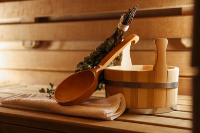 Photo of Ladle, towel, bucket and whisk on wooden bench in sauna