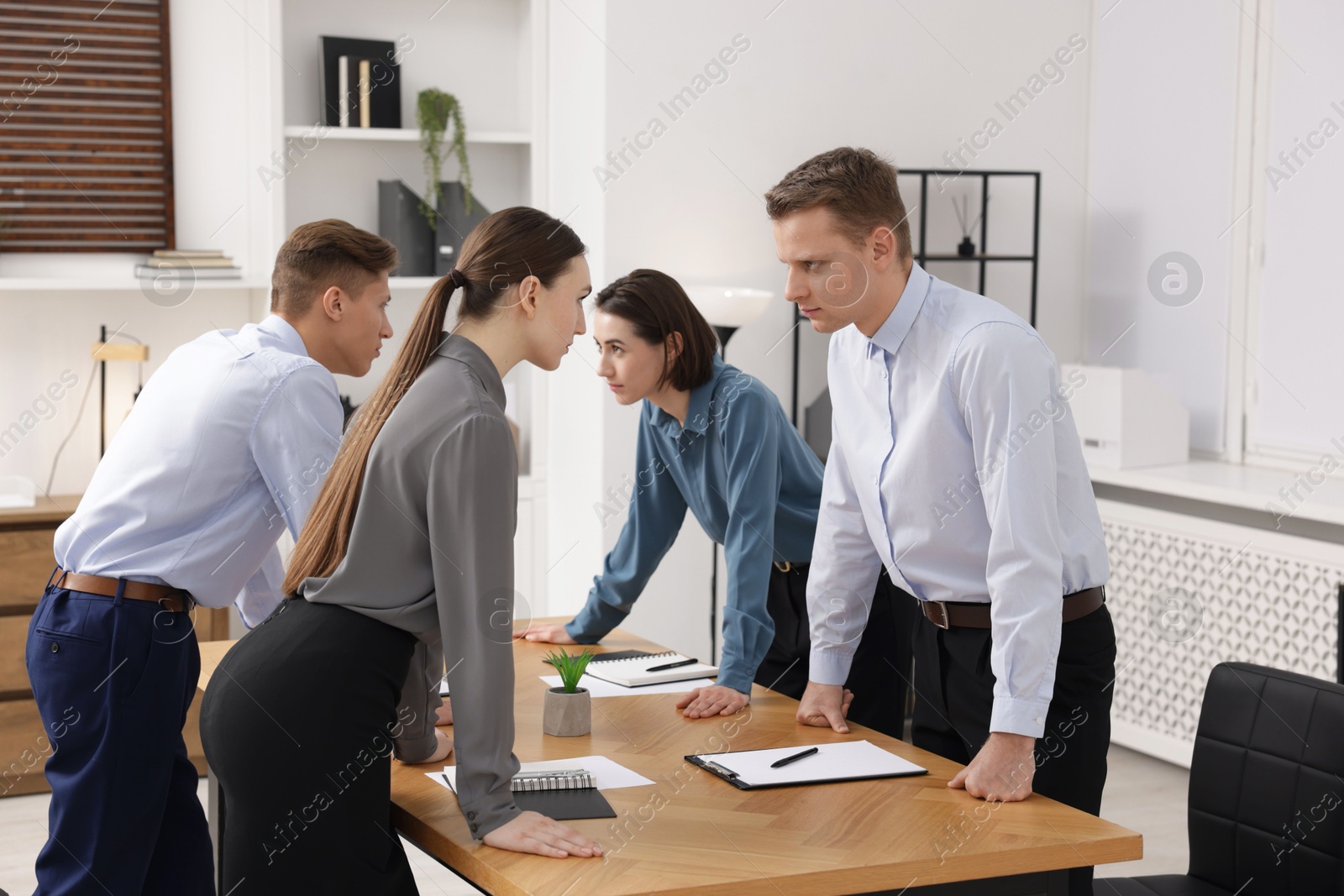 Photo of Competition concept. Group of businesspeople looking and examining each other at table in office