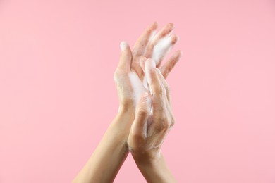 Photo of Woman washing hands with foaming soap on pink background, closeup. Hygiene