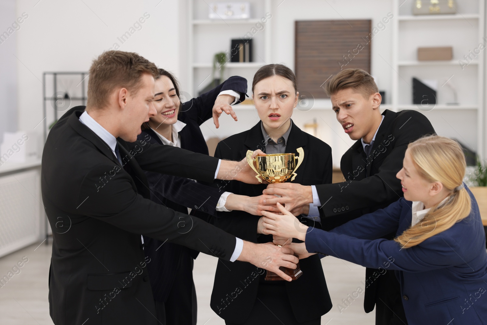 Photo of Competition concept. Group of businesspeople with golden trophy in office