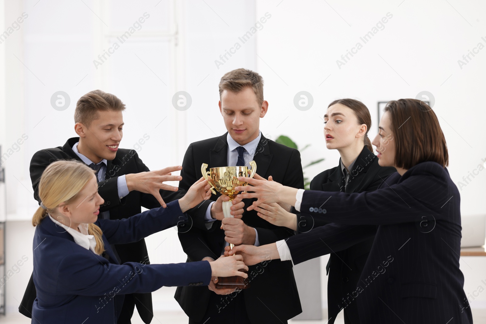 Photo of Competition concept. Group of businesspeople with golden trophy in office