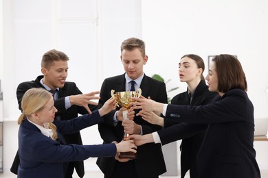 Competition concept. Group of businesspeople with golden trophy in office