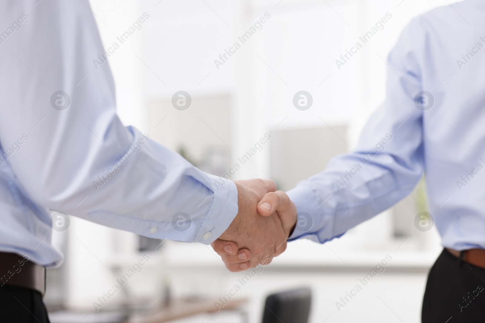 Photo of Businessmen shaking hands in agreement indoors, closeup