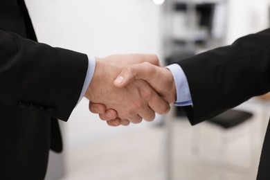 Businessmen shaking hands in agreement indoors, closeup