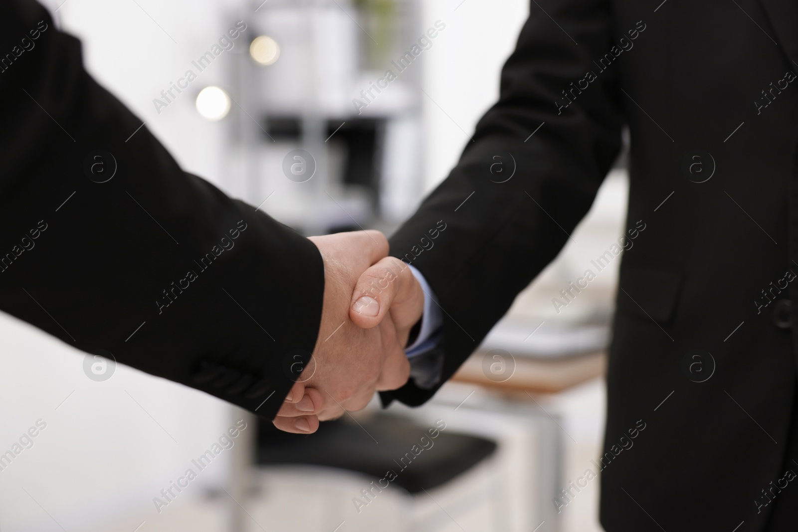 Photo of Businessmen shaking hands in agreement indoors, closeup