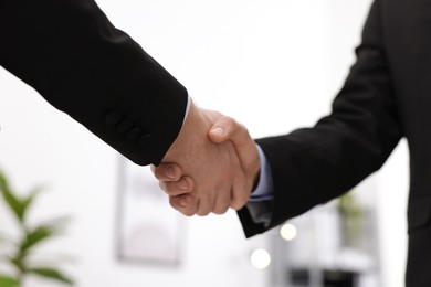 Photo of Businessmen shaking hands in agreement indoors, closeup