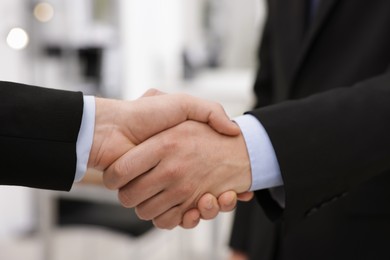 Photo of Businessmen shaking hands in agreement indoors, closeup