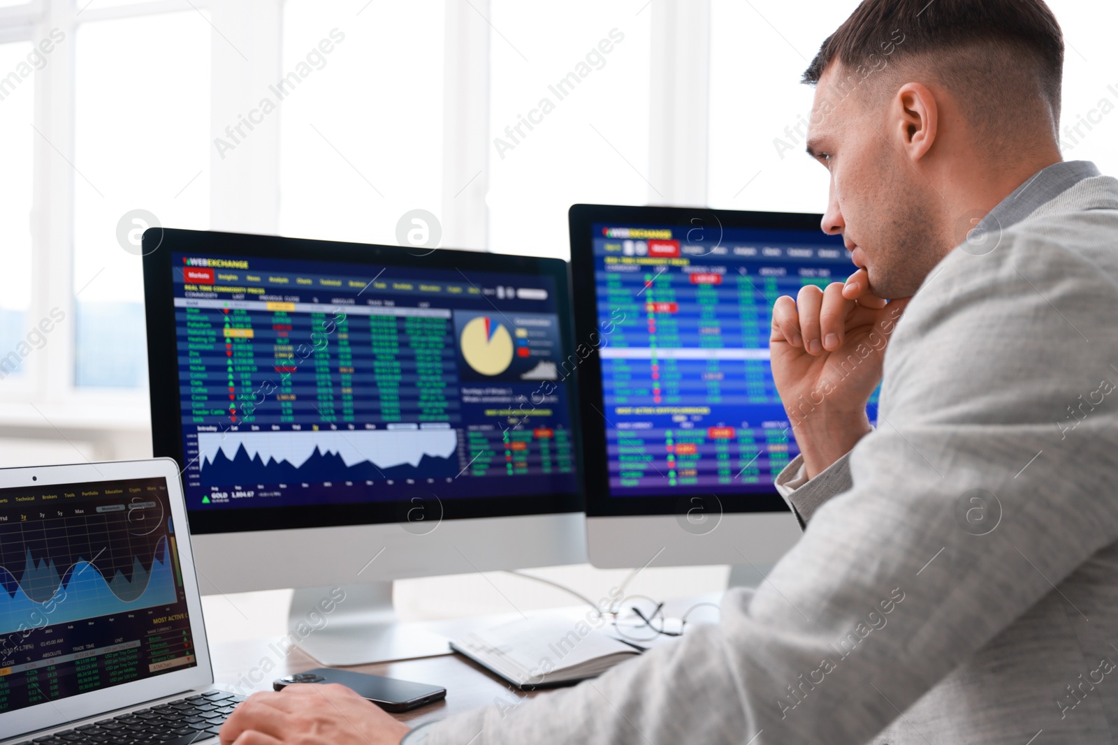 Photo of Financial trading specialist working on computer and laptop in office