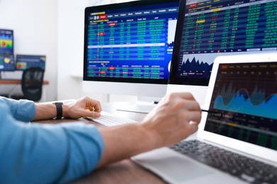 Photo of Financial trading specialist working on laptop at table in office, closeup