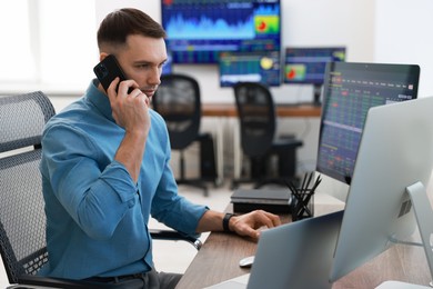 Financial trading specialist talking on phone in office