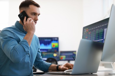 Financial trading specialist talking on phone in office