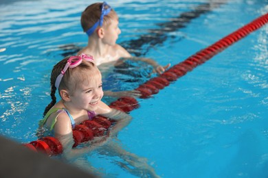 Photo of Children with goggles swimming in pool indoors, selective focus