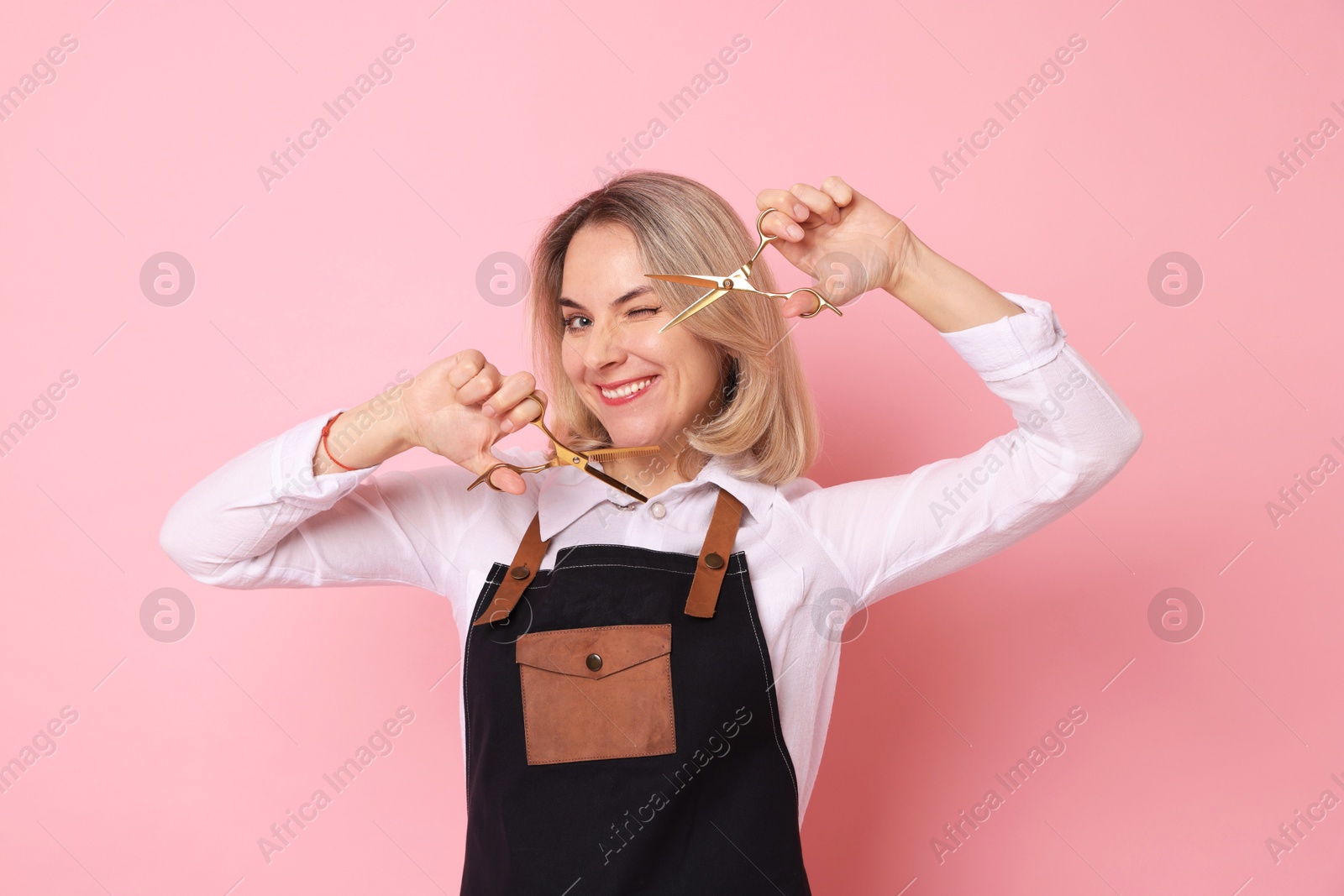 Photo of Smiling hairdresser with scissors on pink background