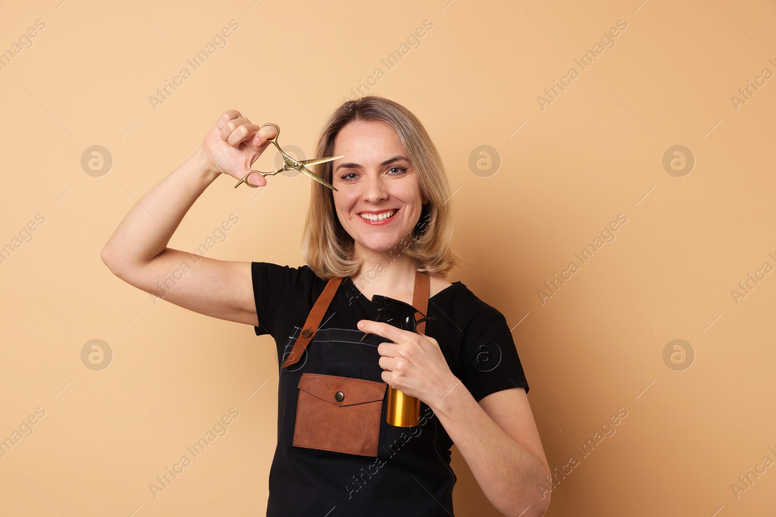 Photo of Smiling hairdresser with scissors and spray bottle on beige background