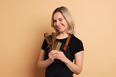 Smiling hairdresser with combs on beige background