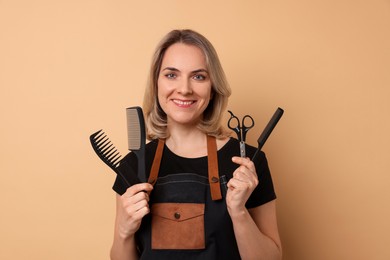 Smiling hairdresser with combs and scissors on beige background