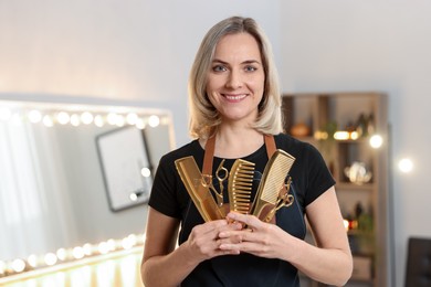 Photo of Smiling hairdresser with scissors and combs in beauty salon