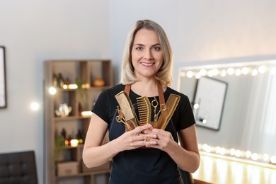 Smiling hairdresser with scissors and combs in beauty salon