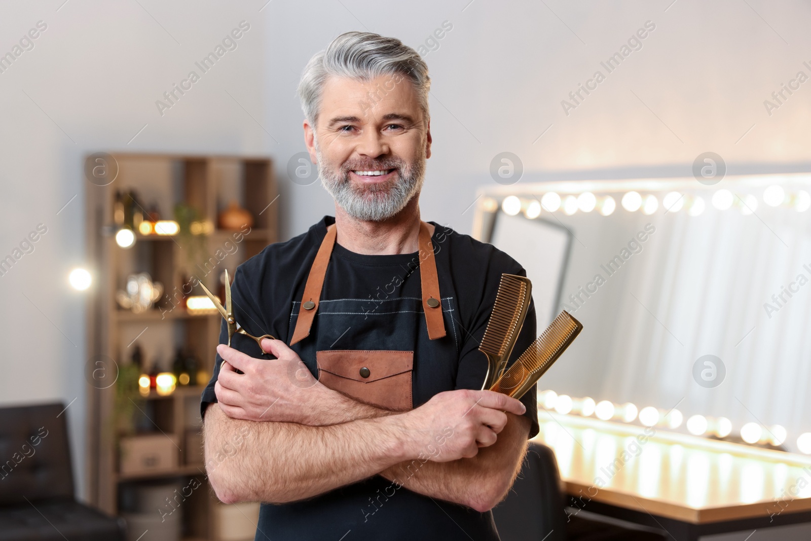 Photo of Smiling hairdresser with combs and scissors in beauty salon