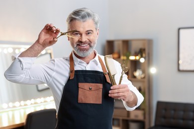 Photo of Smiling hairdresser with scissors and comb in beauty salon