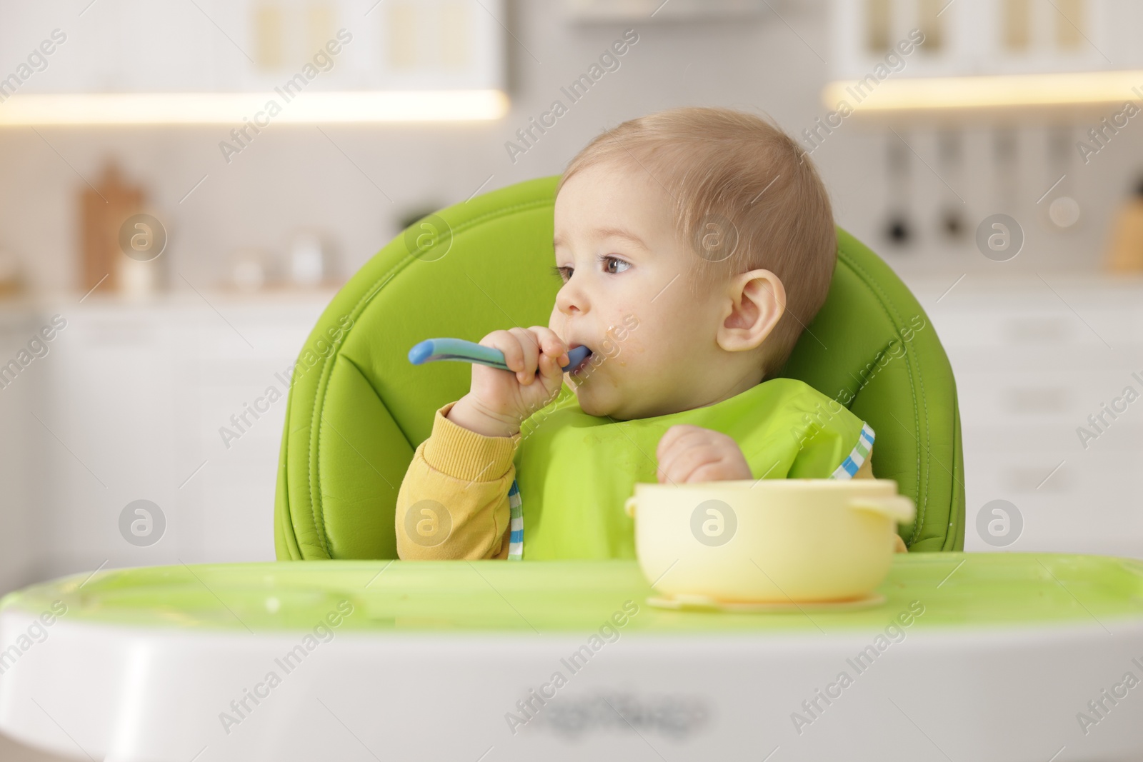 Photo of Cute little baby eating healthy food in high chair indoors