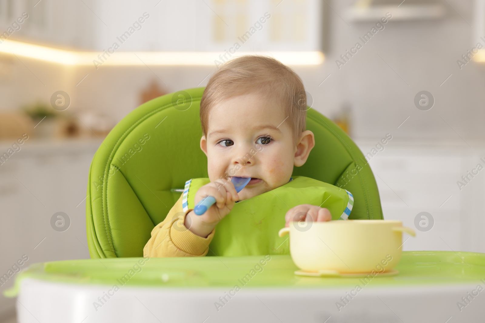 Photo of Cute little baby eating healthy food in high chair indoors