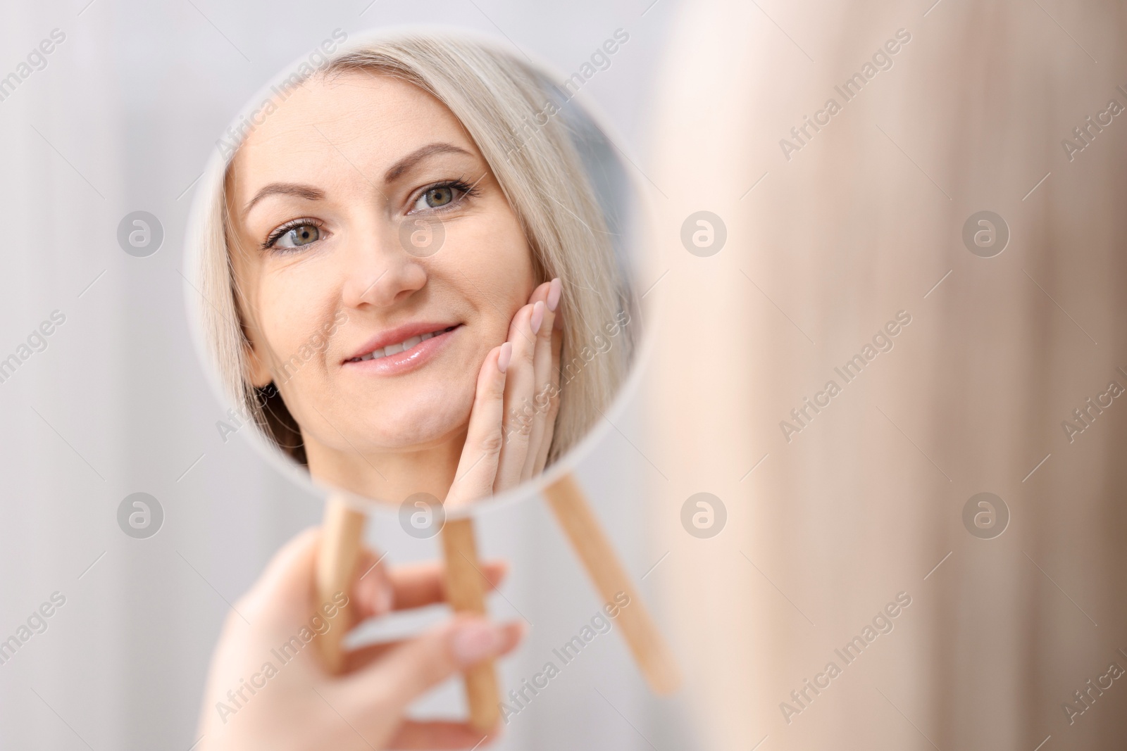 Photo of Beautiful woman looking at herself in mirror indoors