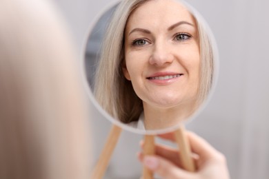 Photo of Beautiful woman looking at herself in mirror indoors