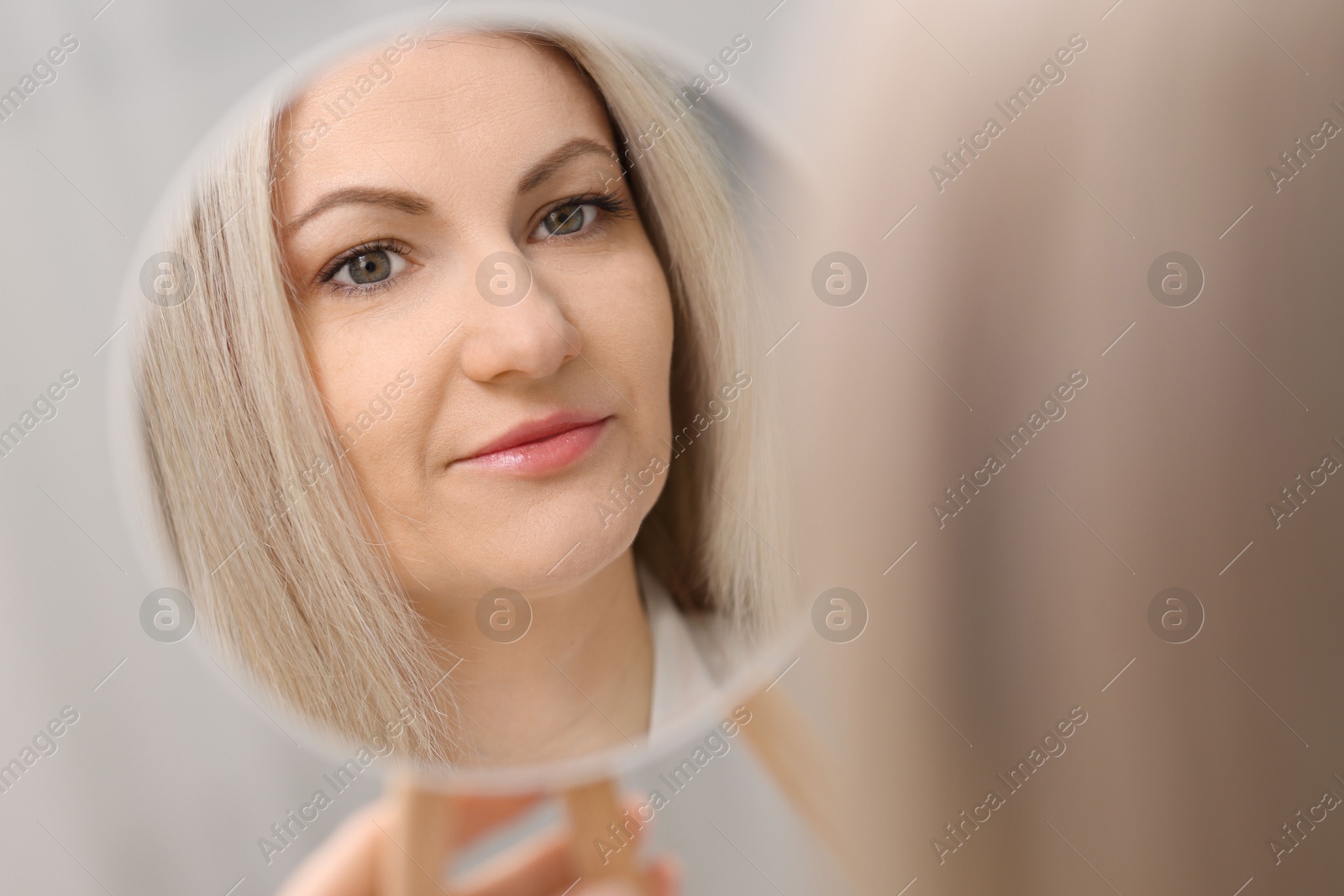 Photo of Beautiful woman looking at herself in mirror indoors