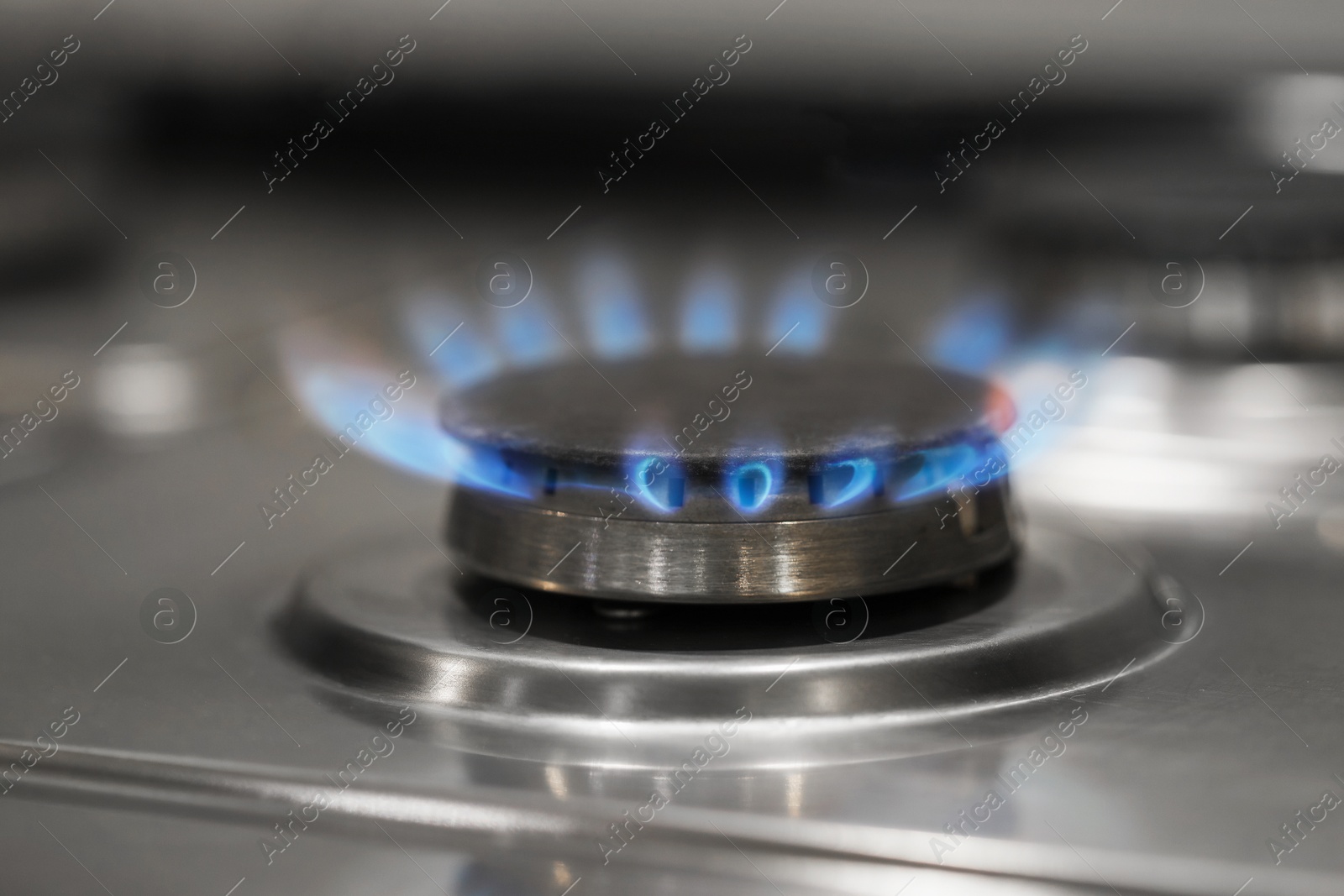 Photo of Gas burner with blue flame on stove, closeup