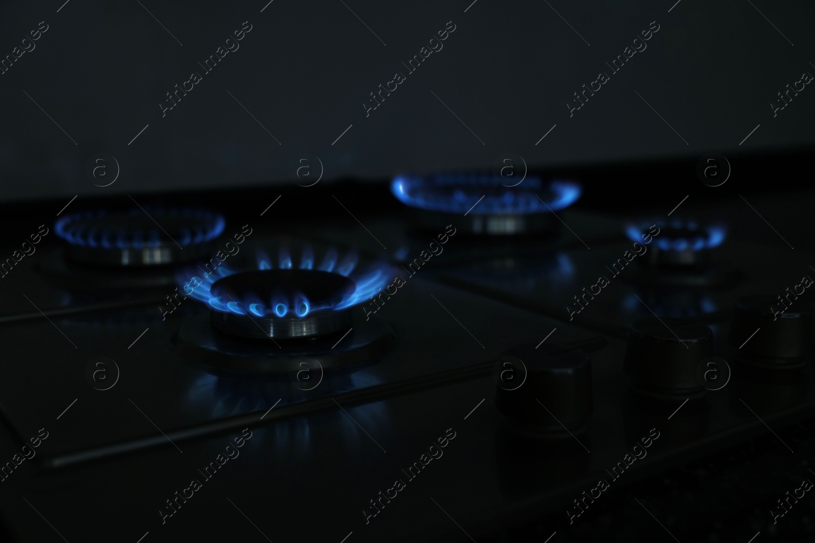 Photo of Gas burners with blue flame on stove, closeup