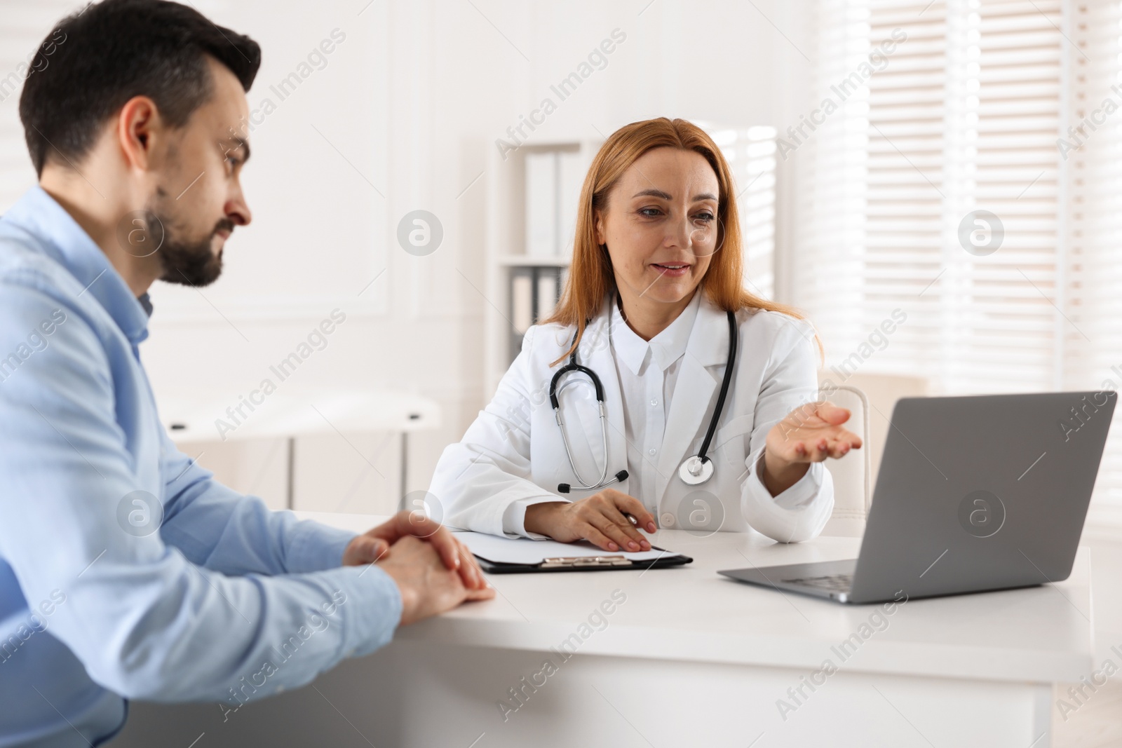 Photo of Man having consultation with cardiologist at desk in clinic