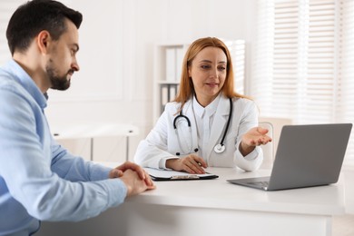 Photo of Man having consultation with cardiologist at desk in clinic