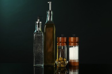 Photo of Salad dressings, spices and olives on mirror surface against black background