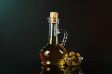 Photo of Oil in bottle and olives on mirror surface against black background