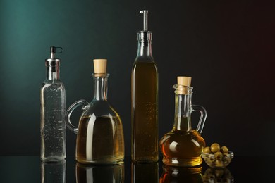 Photo of Salad dressings and olives on mirror surface against black background