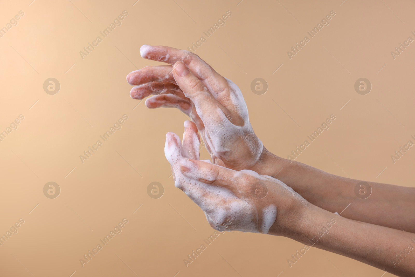 Photo of Woman washing hands with foaming soap on beige background, closeup. Hygiene