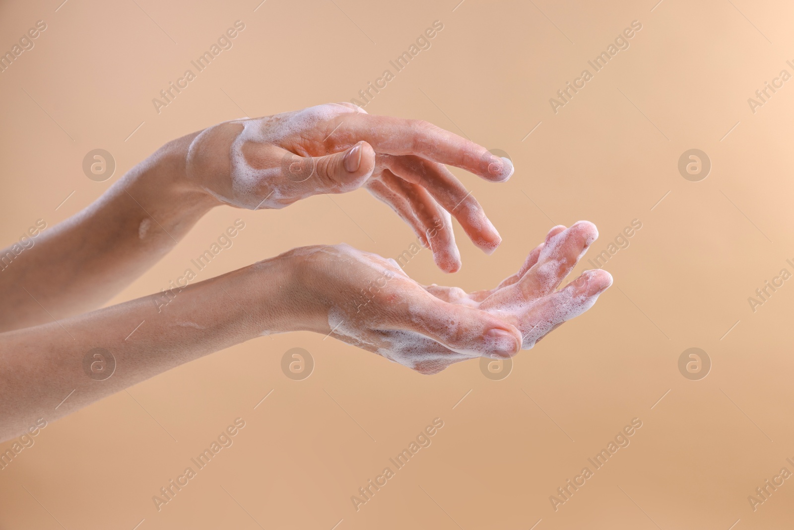 Photo of Woman washing hands with foaming soap on beige background, closeup. Hygiene