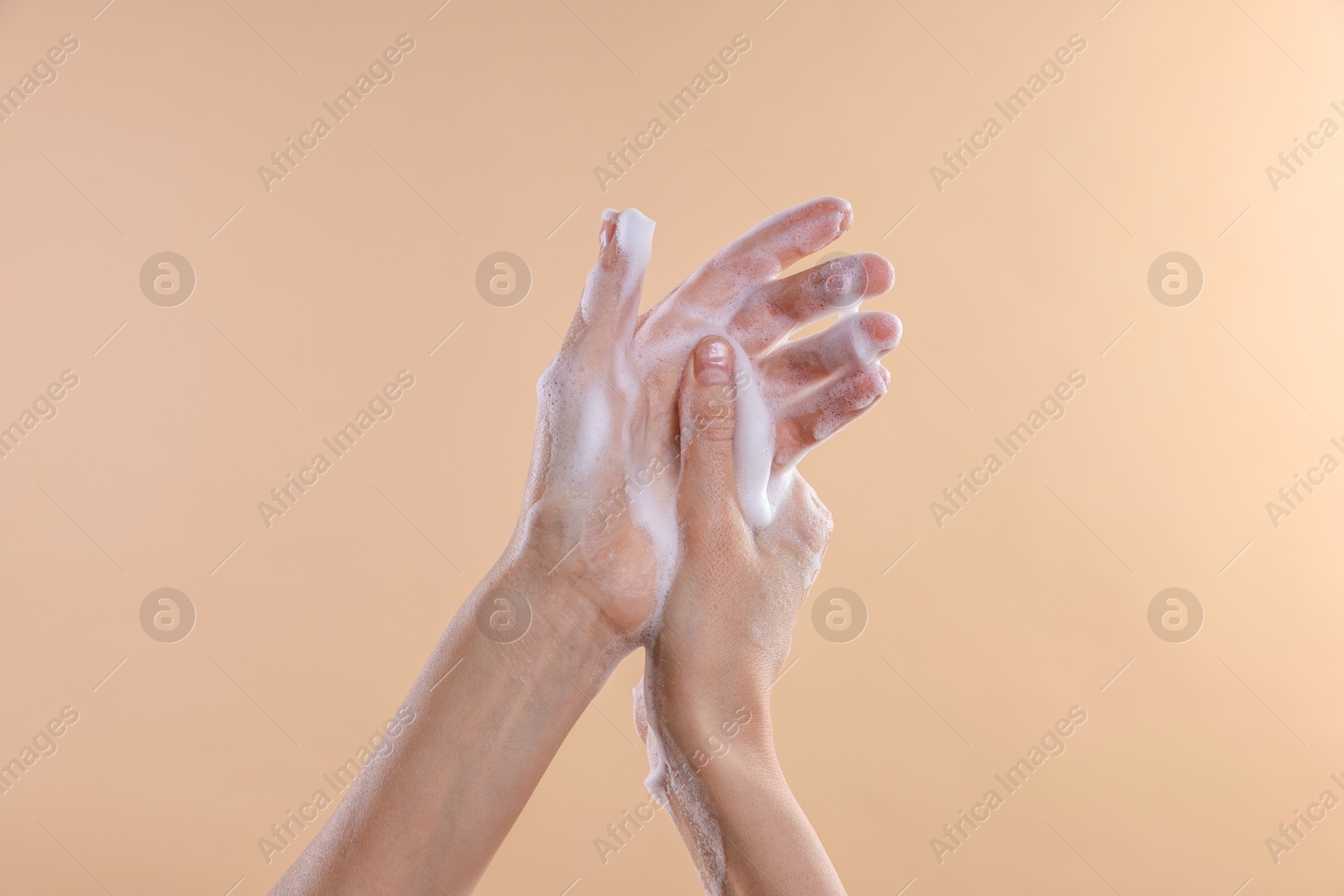 Photo of Woman washing hands with foaming soap on beige background, closeup. Hygiene