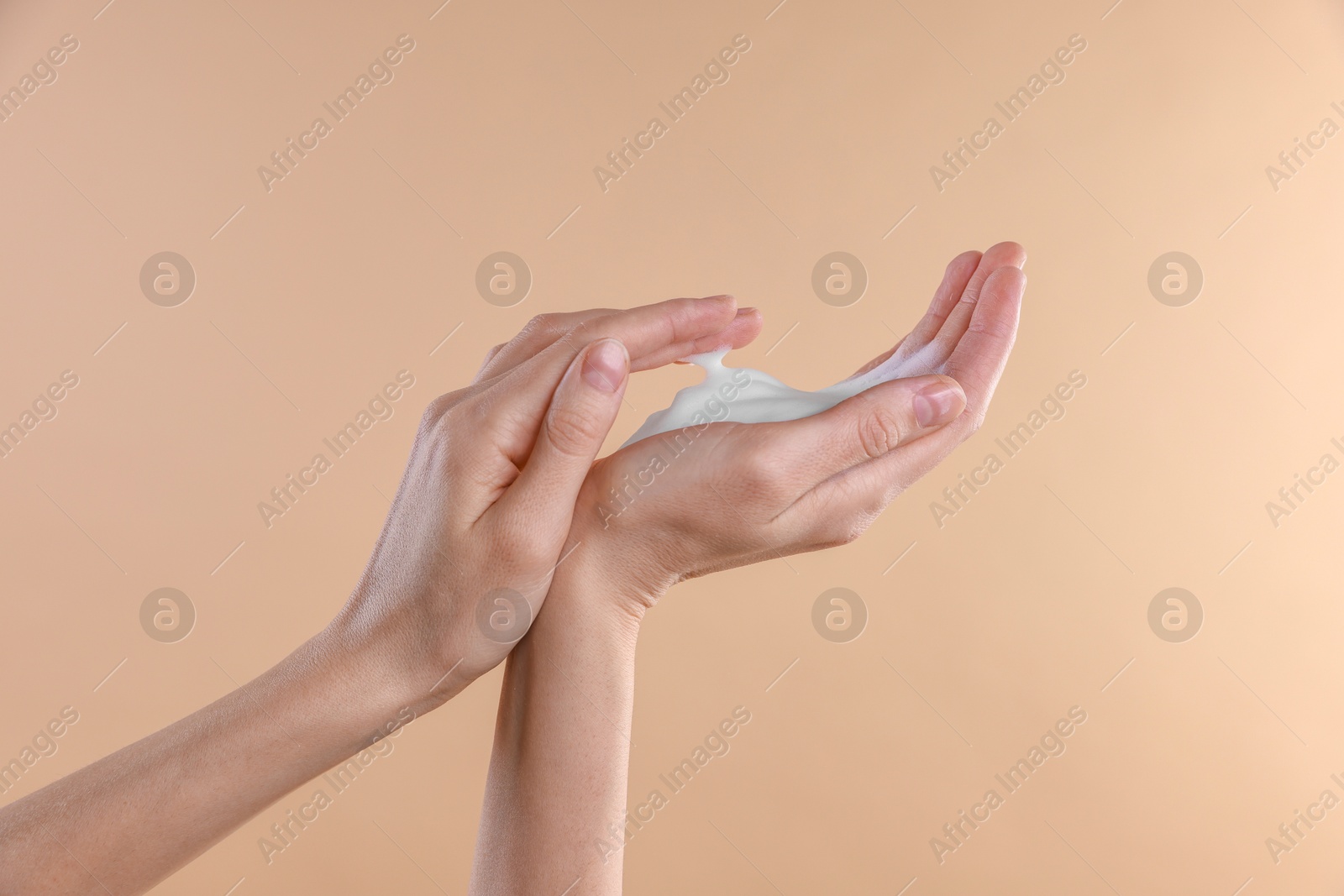 Photo of Woman washing hands with foaming soap on beige background, closeup. Hygiene