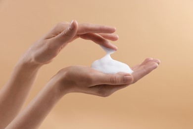 Photo of Woman washing hands with foaming soap on beige background, closeup. Hygiene