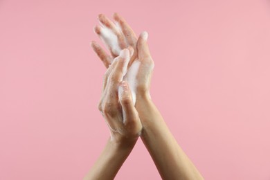 Photo of Woman washing hands with foaming soap on pink background, closeup. Hygiene