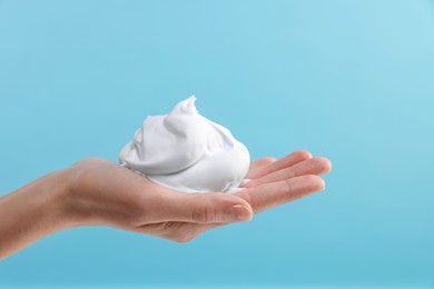 Photo of Woman with cosmetic foam on light blue background, closeup